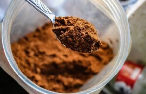 Focused shot of a spoon scooping cocoa powder from a container, emphasizing texture.