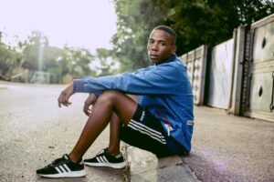 Young man sitting outdoors in sportswear, embodying style and confidence.