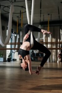 Woman practicing aerial yoga in studio, displaying strength and flexibility.