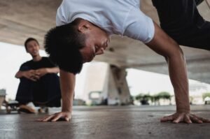 A young man skillfully performing a breakdance move in an urban setting, showcasing agility and strength.